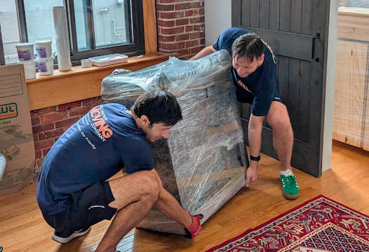WellKnown movers shrink-wrapping a sofa before carrying it out